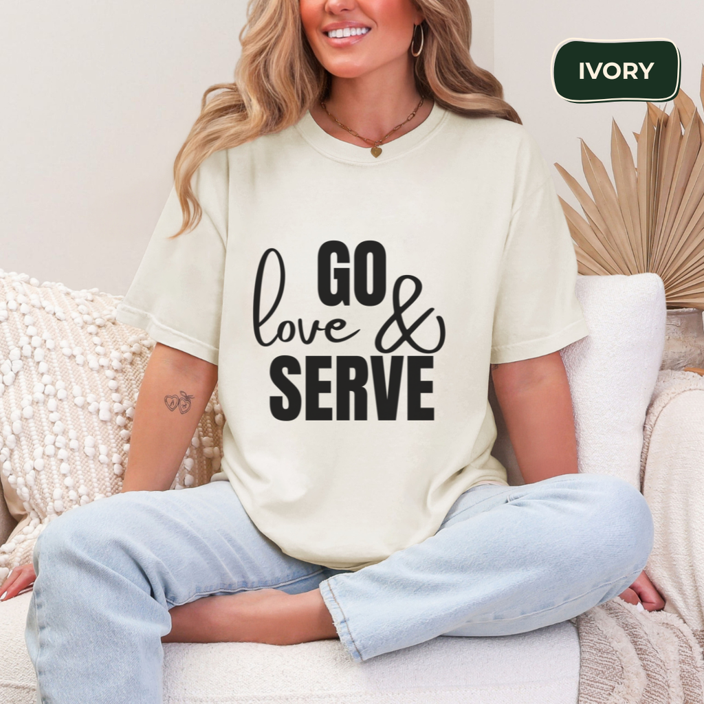 Woman wearing a white t-shirt with 'GO love & SERVE' text, sitting on a couch.