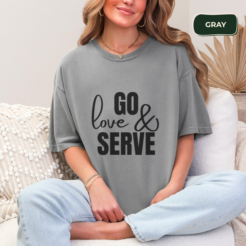 Person wearing a gray t-shirt with 'GO love & SERVE' text, sitting on a couch.