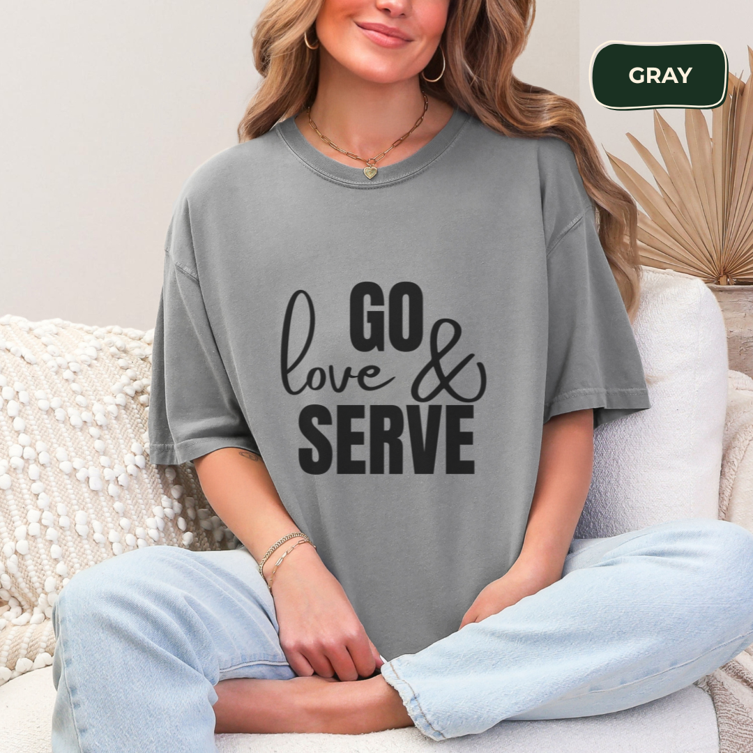 Person wearing a gray t-shirt with 'GO love & SERVE' text, sitting on a couch.