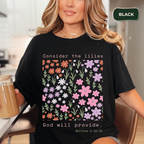 Person wearing a black t-shirt with floral design and text, holding a drink.