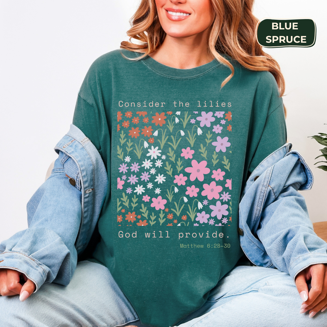 Person wearing a green sweatshirt with floral design and text, sitting on a white background.
