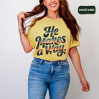 Woman wearing a yellow t-shirt with text and blue jeans, standing against a plain background with 'Mustard' brand logo.