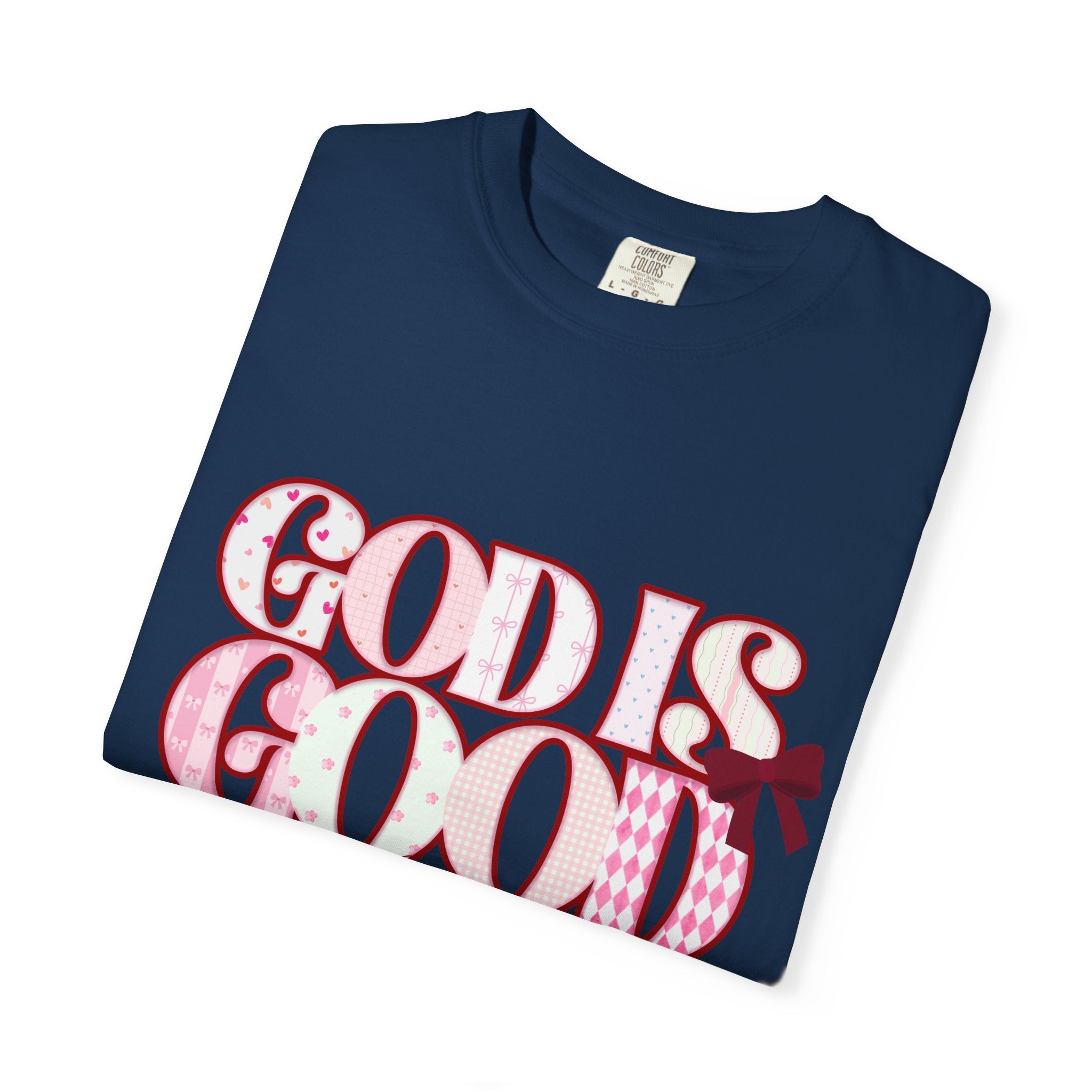 Folded navy blue t-shirt with 'GOD IS GOOD' text in pink and white on a white background